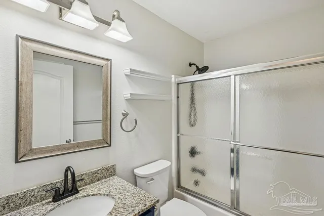 a bathroom with a granite countertop sink toilet and shower