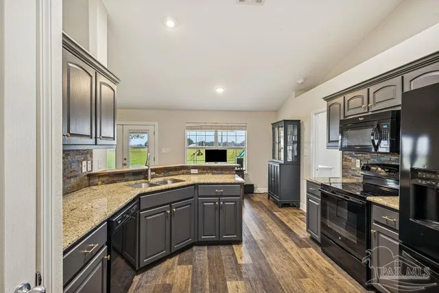 a kitchen with granite countertop a sink stove and refrigerator