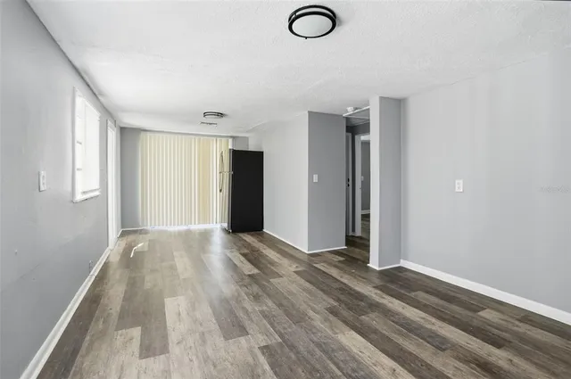 a view of an empty room with window and wooden floor