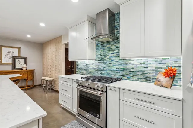 a kitchen with stainless steel appliances white cabinets and a stove top oven
