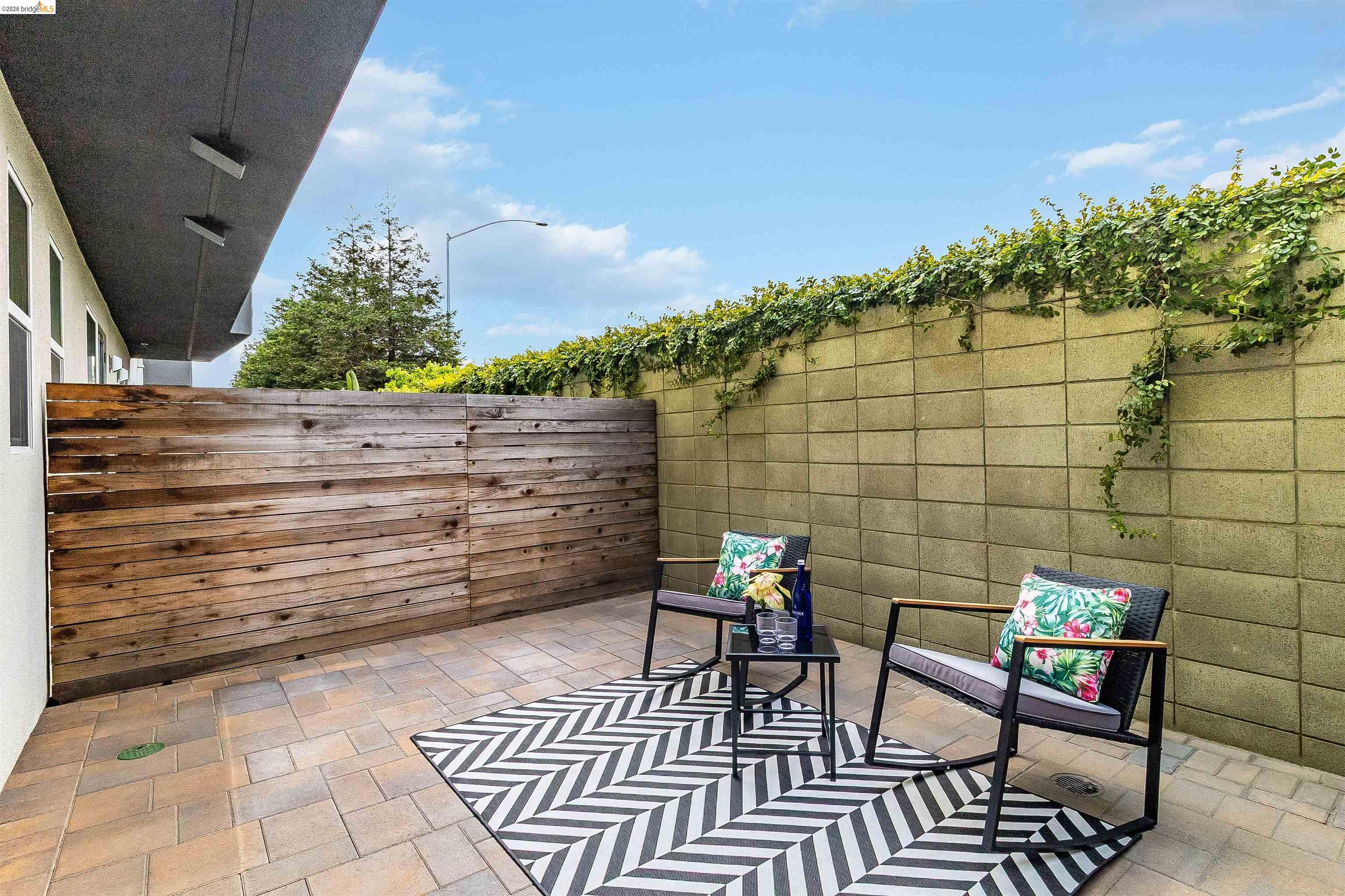 1357 Pullman Way Oakland, CA 94607 - Photo 32 of 37 Paved patio area featuring a horizontal wood fence and a concrete block wall with climbing greenery