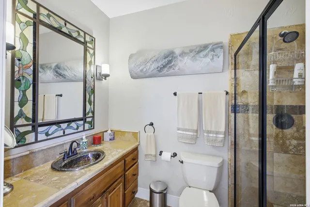 a bathroom with a granite countertop sink a toilet and shower
