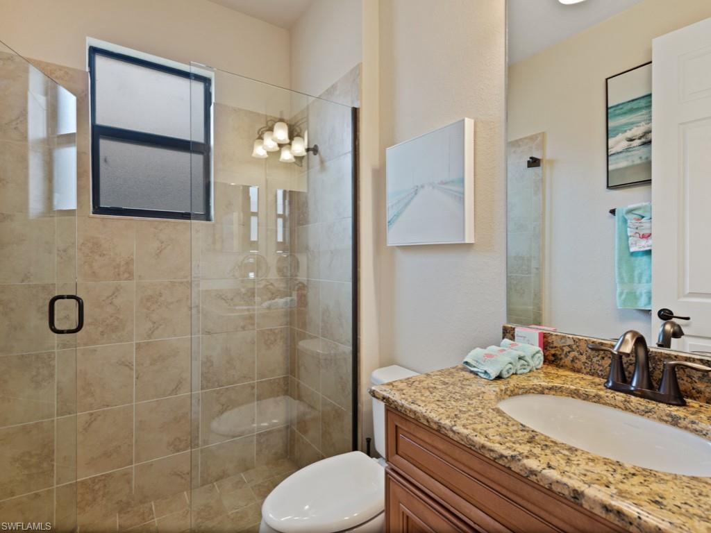 9507 Piacere Way Naples, FL 34113 - Photo 14 of 32 a bathroom with a granite countertop sink toilet mirror and shower