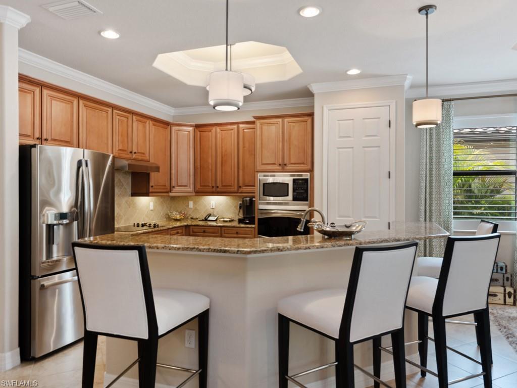 9507 Piacere Way Naples, FL 34113 - Photo 10 of 32 a kitchen with stainless steel appliances granite countertop a stove a refrigerator a oven a sink with a dining table and chairs