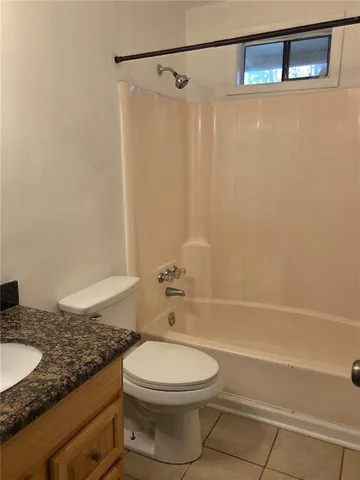 a bathroom with a granite countertop bathtub sink vanity mirror and toilet