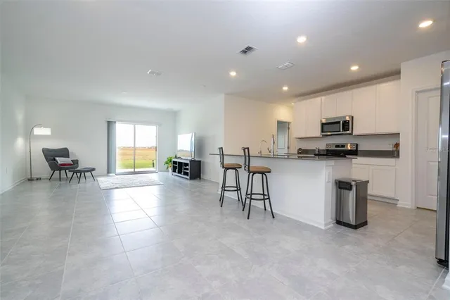 a kitchen with stainless steel appliances granite countertop a stove top oven a sink a dining table and chairs