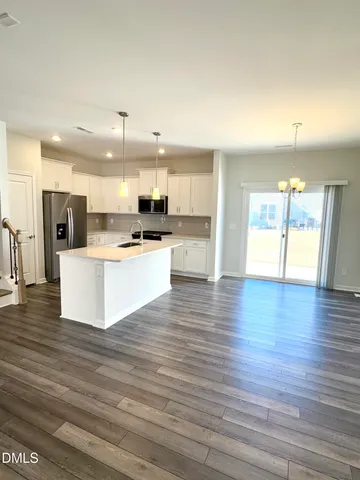 a large kitchen with stainless steel appliances kitchen island a large counter top and a wooden floors
