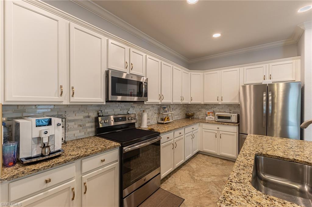 9231 Shadow Oak Lane Naples, FL 34120 - Photo 19 of 46 a kitchen with granite countertop a sink a stove top oven a refrigerator and white cabinets