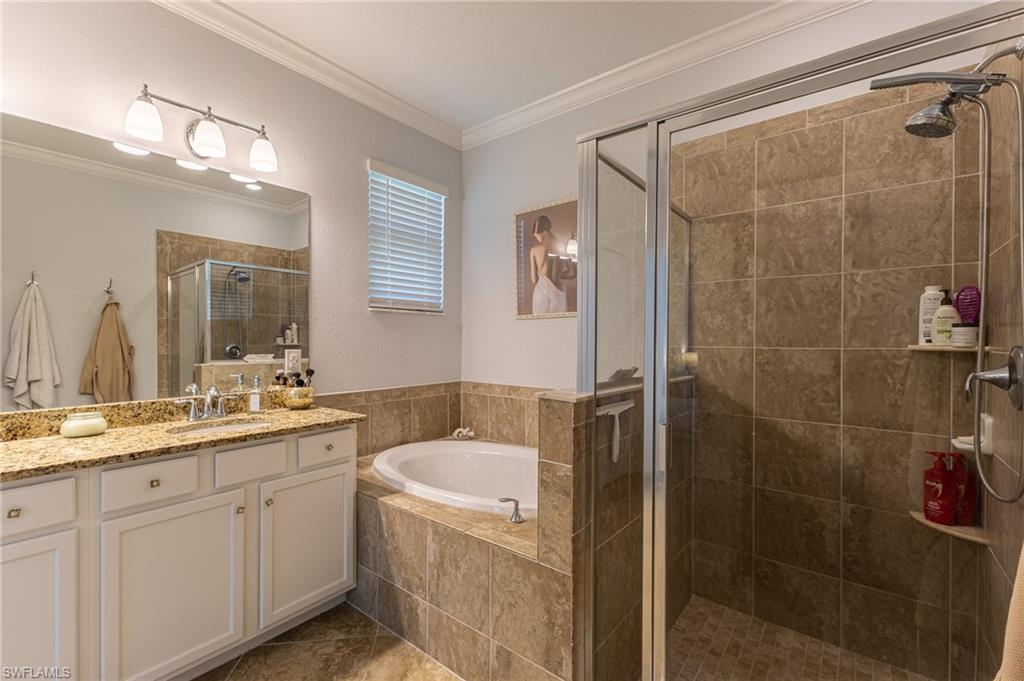 9231 Shadow Oak Lane Naples, FL 34120 - Photo 26 of 46 a bathroom with a granite countertop sink a mirror a bathtub and shower