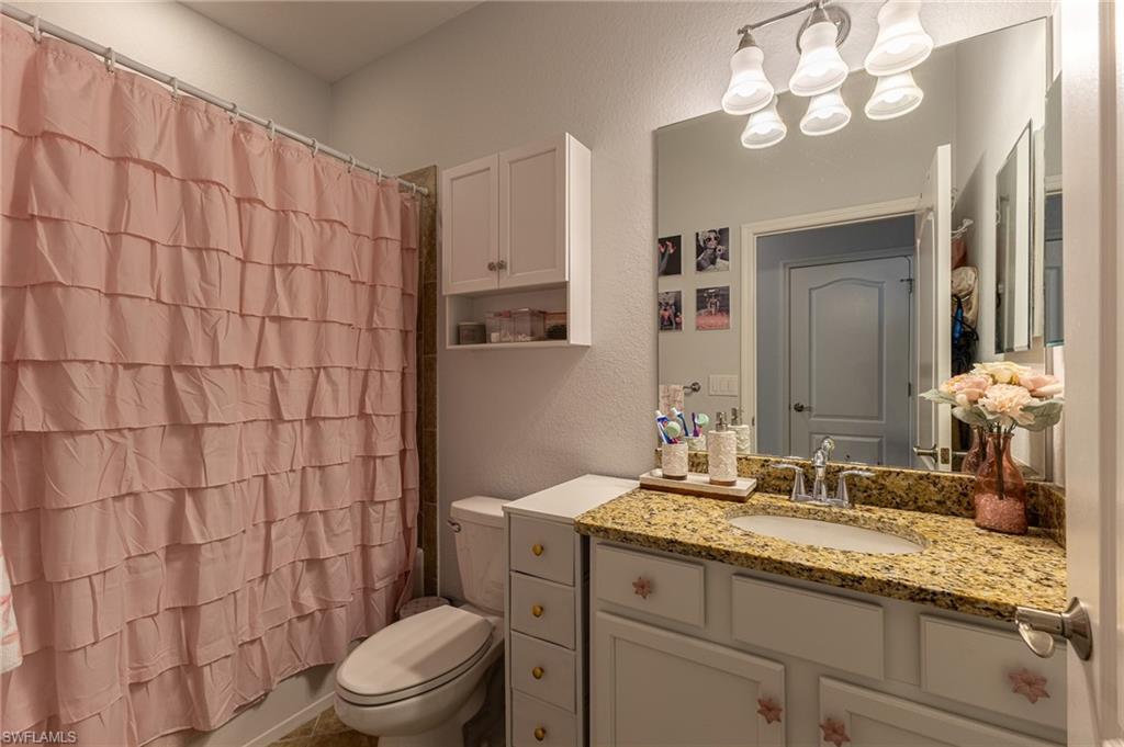 9231 Shadow Oak Lane Naples, FL 34120 - Photo 28 of 46 a bathroom with a granite countertop sink a toilet and a mirror
