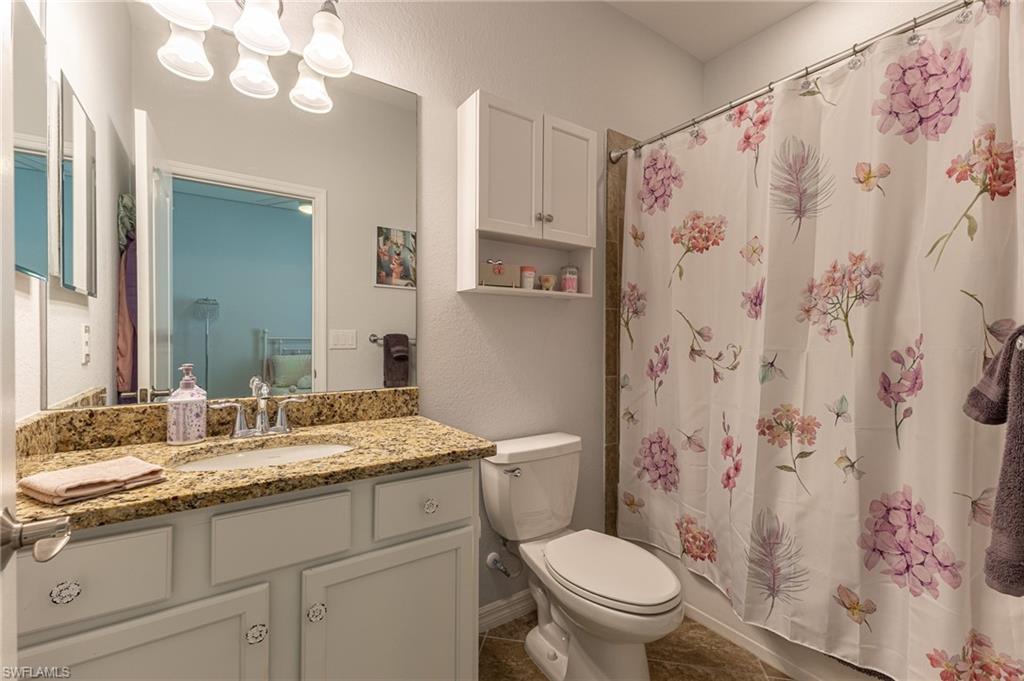 9231 Shadow Oak Lane Naples, FL 34120 - Photo 29 of 46 a bathroom with a granite countertop sink toilet a mirror a vanity and a shower