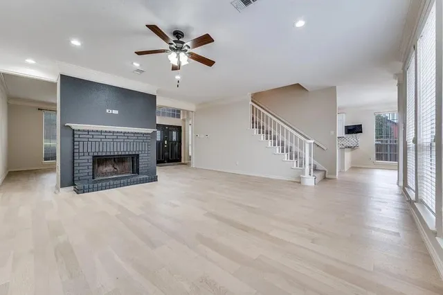a view of an empty room with wooden floor a fireplace and a window