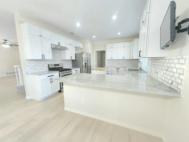 a kitchen with stainless steel appliances granite countertop a sink a stove and a refrigerator