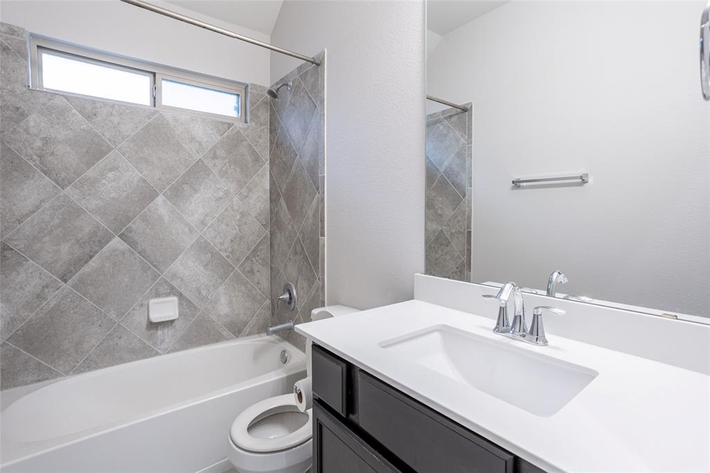 615 Stampede Road San Marcos, TX 78666 - Photo 4 of 26 A well-appointed bathroom features a single vanity, a standard tub, and a shower with tiled surround, creating a clean and functional space.