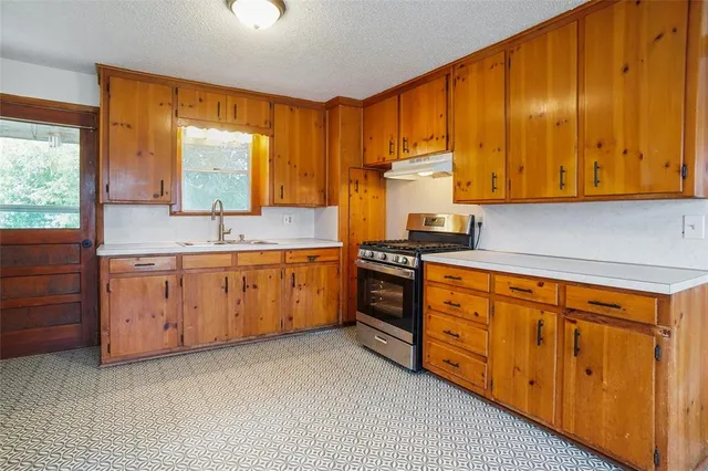 a kitchen with stainless steel appliances a sink window and cabinets