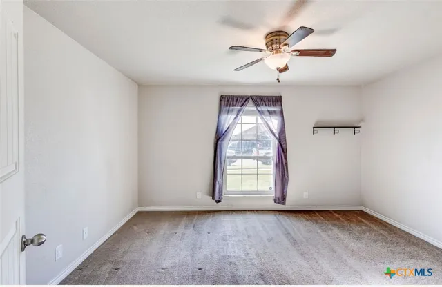 an empty room with windows and fan