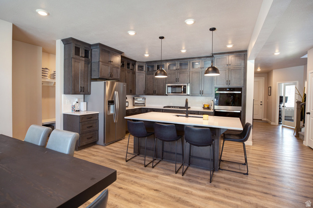 983 South 950 West Provo, UT 84601 - Photo 4 of 56 Spacious kitchen featuring gray cabinetry, stainless steel appliances, a center island with seating, and wood-finish flooring