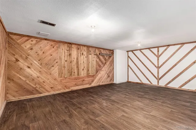 a view of an empty room with wooden floor and stairs