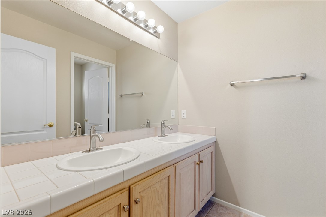 9034 Ridgepointe Way Henderson, NV 89074 - Photo 36 of 56 Clean lines define a functional vanity space complete with dual sinks and classic tiled countertops.
