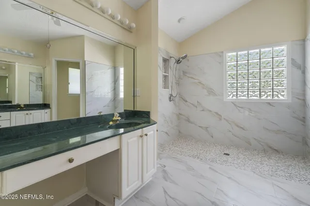 a bathroom with a granite countertop sink a mirror and a shower