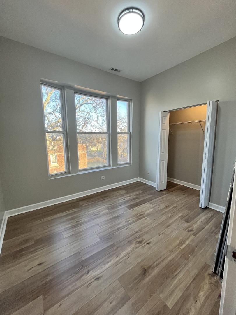 501 West 60th Place, Unit 3 Chicago, IL 60621 - Photo 8 of 12 an empty room with wooden floor and windows