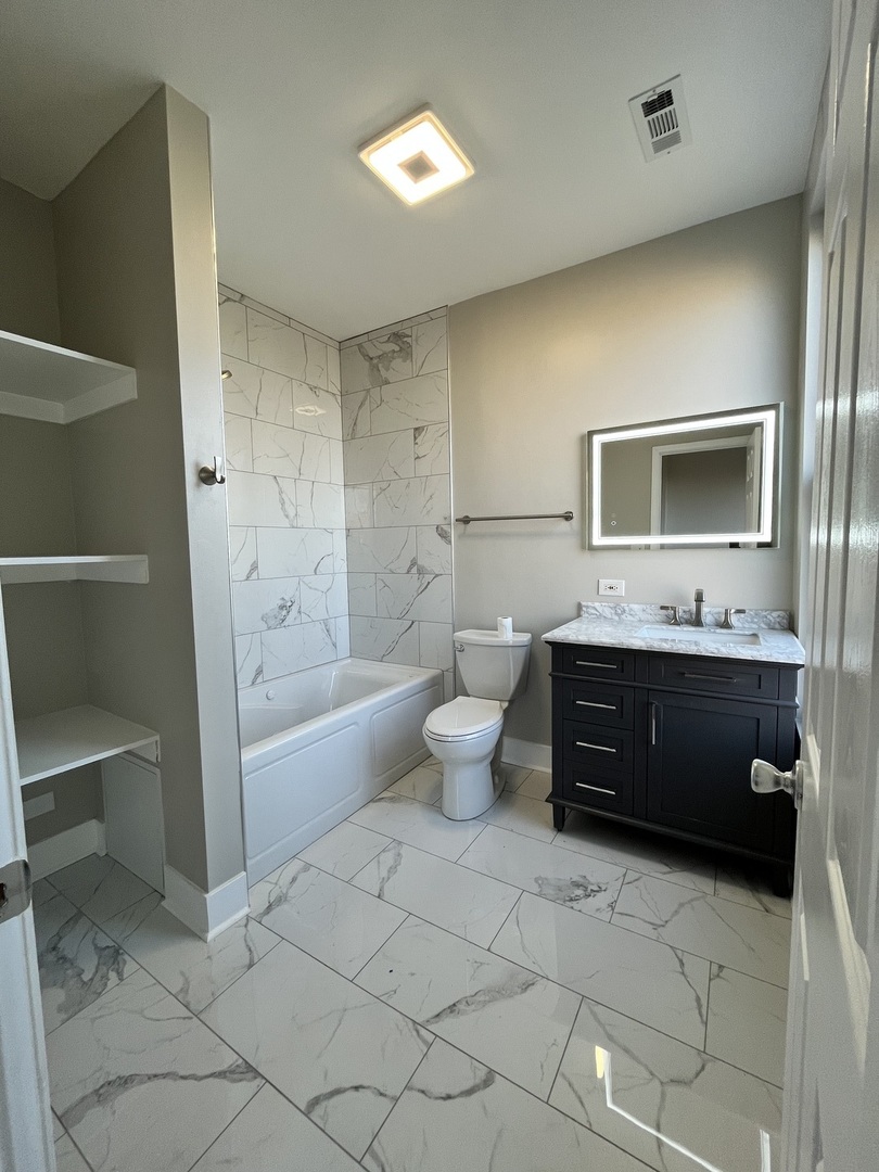 501 West 60th Place, Unit 3 Chicago, IL 60621 - Photo 9 of 12 a bathroom with a tub sink toilet and mirror