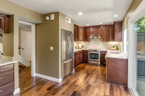 a kitchen with stainless steel appliances granite countertop a refrigerator a stove and a wooden floors