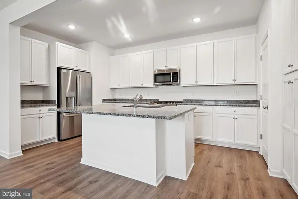 a kitchen with stainless steel appliances granite countertop a refrigerator sink and white cabinets