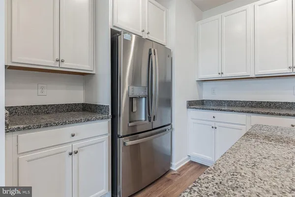 a kitchen with granite countertop a refrigerator sink and cabinets