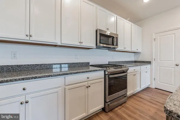 a kitchen with granite countertop white cabinets stainless steel appliances and sink
