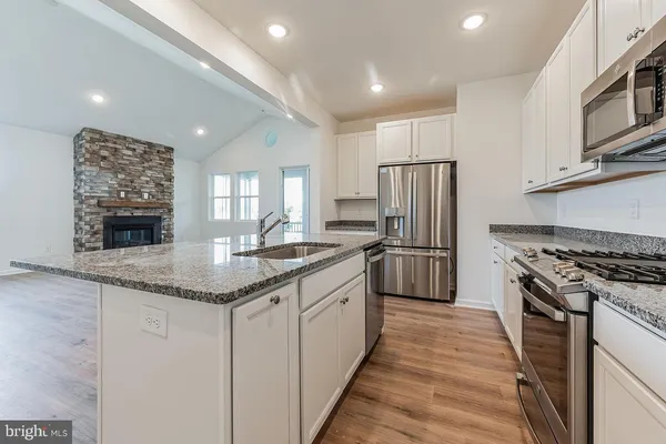 a kitchen with stainless steel appliances granite countertop a stove a sink dishwasher a refrigerator and a oven with wooden floor