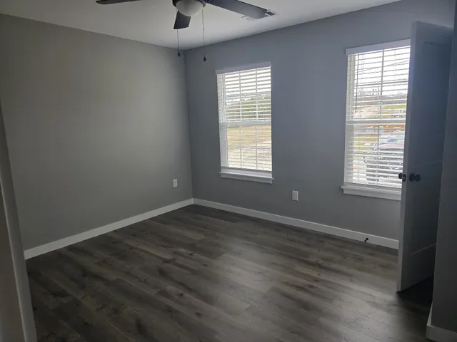 an empty room with wooden floor and windows