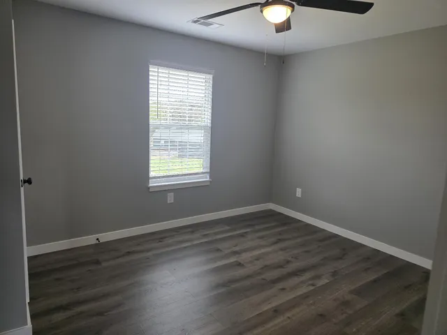 an empty room with wooden floor and windows