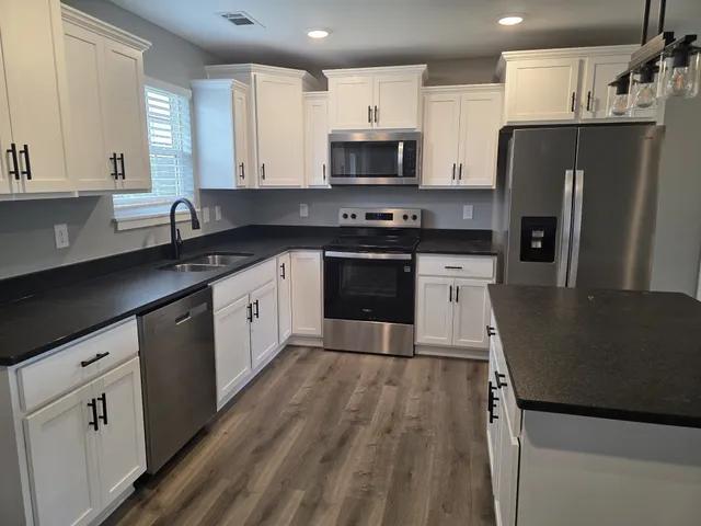 a kitchen with a sink a microwave a refrigerator and cabinets