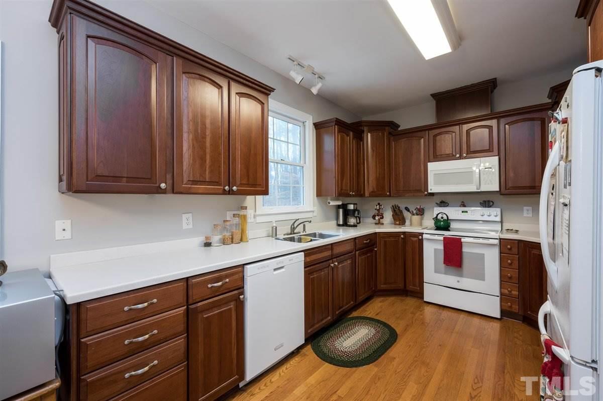 5704 Dunstan Court Raleigh, NC 27613 - Photo 10 of 23 a kitchen with stainless steel appliances granite countertop wooden cabinets a stove a sink and dishwasher with wooden floor