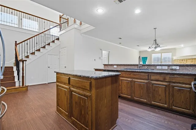 a kitchen with stainless steel appliances granite countertop a sink a stove and a wooden floors