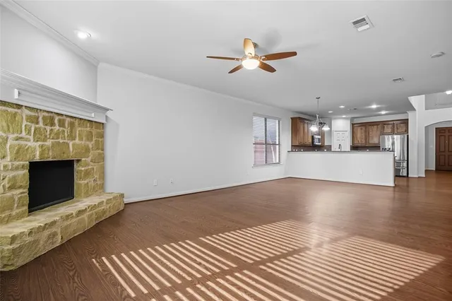 a view of a livingroom with a fireplace a ceiling fan and windows