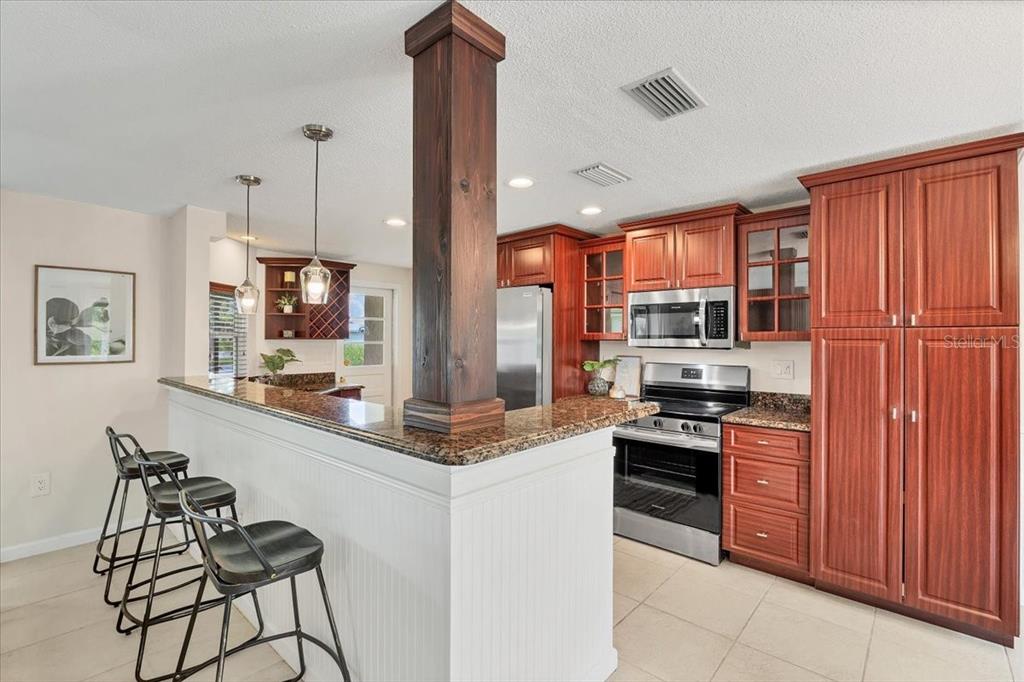 4696 Pompano Street Placida, FL 33946 - Photo 10 of 23 a kitchen with stainless steel appliances granite countertop a stove top oven a sink dishwasher and a refrigerator with wooden cabinets