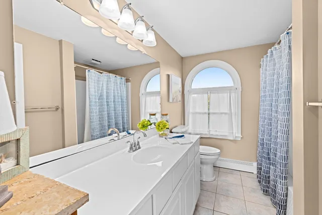 a spacious bathroom with a granite countertop sink a toilet and a bathtub