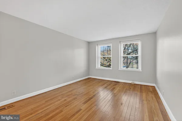 a view of a kitchen and an empty room with wooden floor and a window