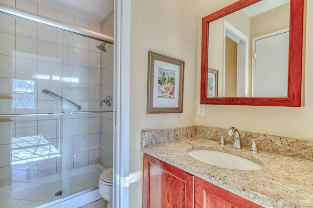a bathroom with a granite countertop sink a mirror and a shower