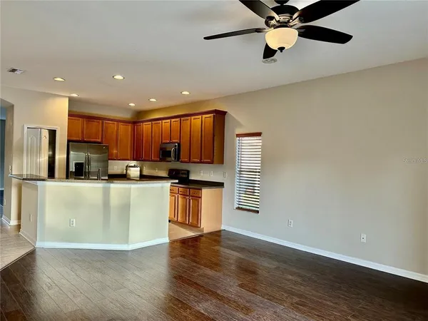 a kitchen with granite countertop wooden floors stainless steel appliances a sink and a window