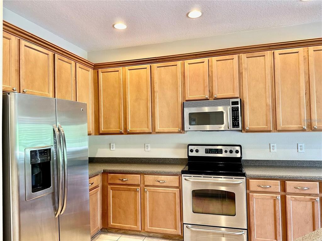 9249 Edistro Place New Port Richey, FL 34654 - Photo 16 of 82 a kitchen with stainless steel appliances granite countertop a stove a microwave and a refrigerator