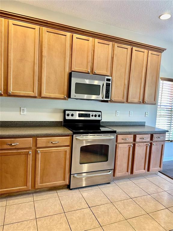 9249 Edistro Place New Port Richey, FL 34654 - Photo 17 of 82 a kitchen with granite countertop a stove top oven microwave and cabinets