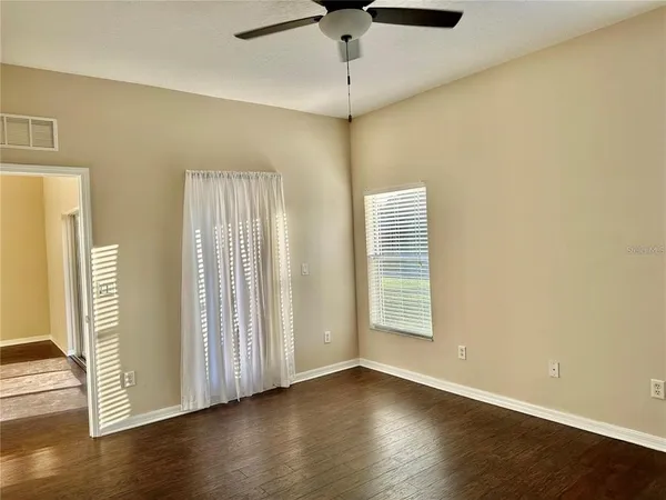 an empty room with wooden floor and windows