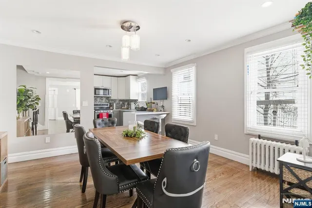 a dining room with kitchen island stainless steel appliances furniture a window and dining table