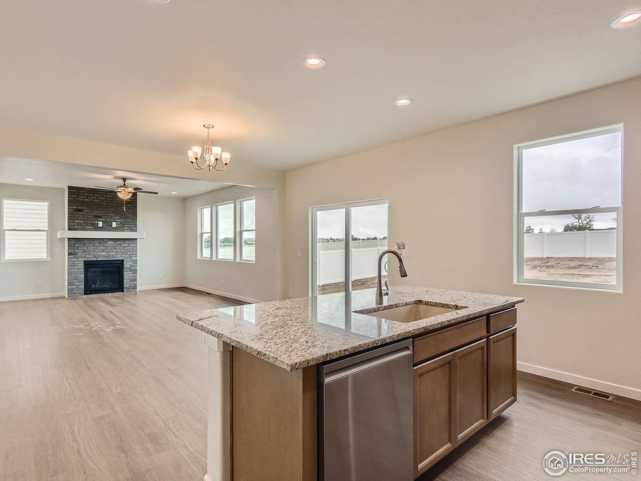 2538 Doe Rdg Way Johnstown, CO 80534 - Photo 12 of 28 a kitchen with granite countertop kitchen island a sink dishwasher a fireplace with wooden cabinets and floor