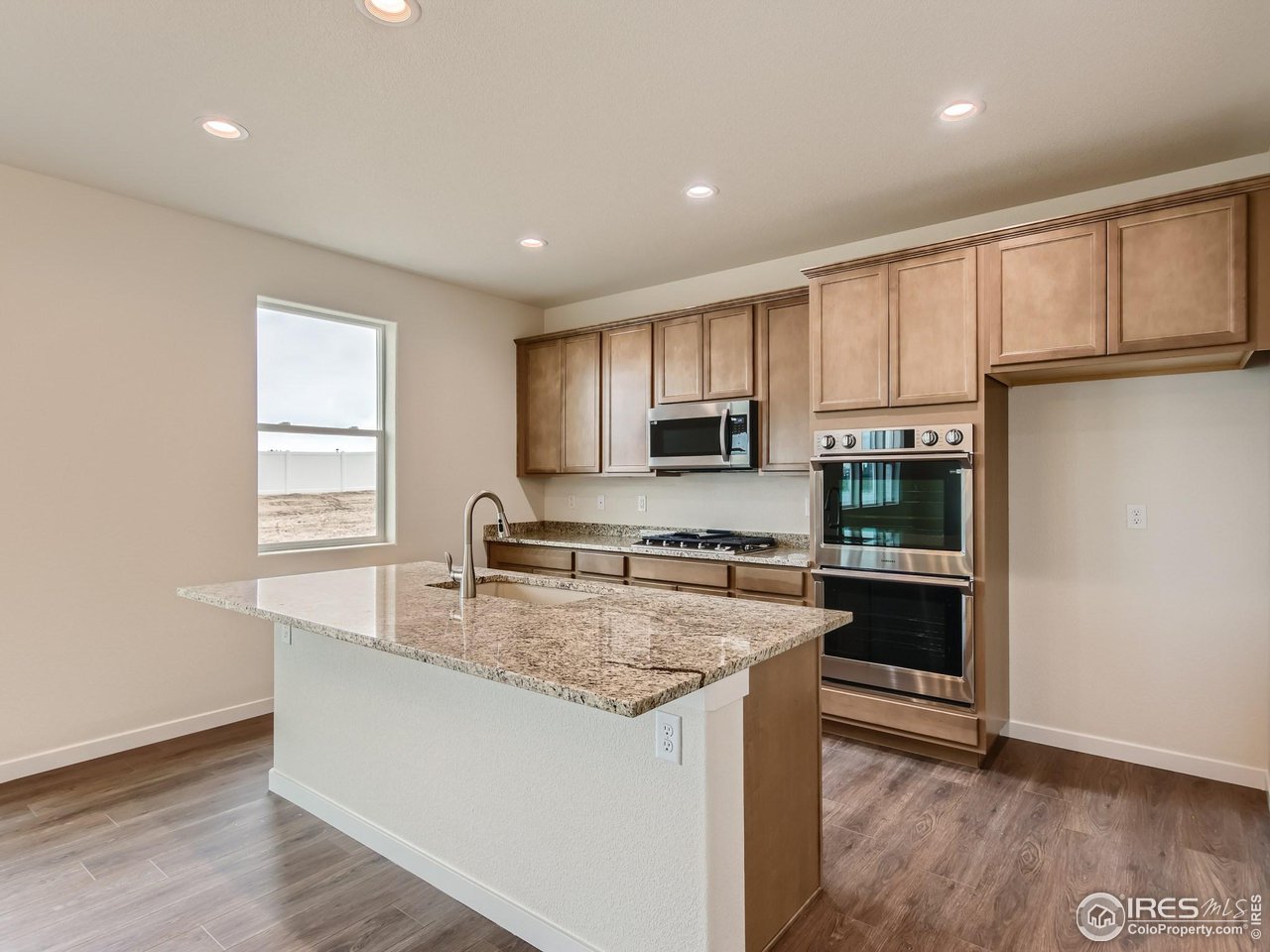 2538 Doe Rdg Way Johnstown, CO 80534 - Photo 9 of 28 a kitchen with stainless steel appliances granite countertop a stove a sink a refrigerator white cabinets and wooden floor