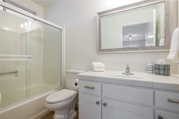 a bathroom with a granite countertop sink toilet and mirror