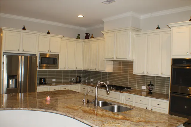 a kitchen with granite countertop a sink a counter top space appliances and cabinets